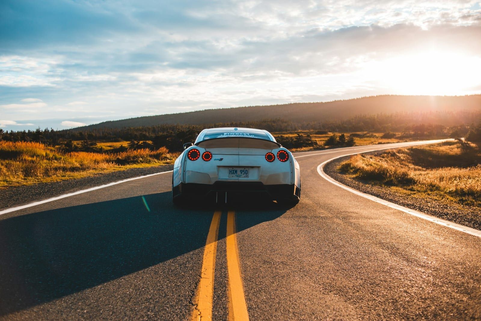 White sports car with a deep gloss finish on a country road at sunset