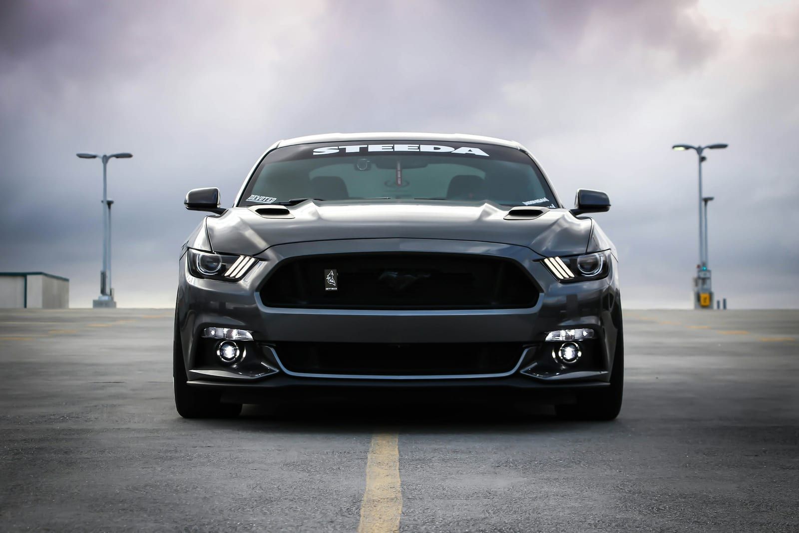 Grey muscle car from the front, with a windshield sun strip