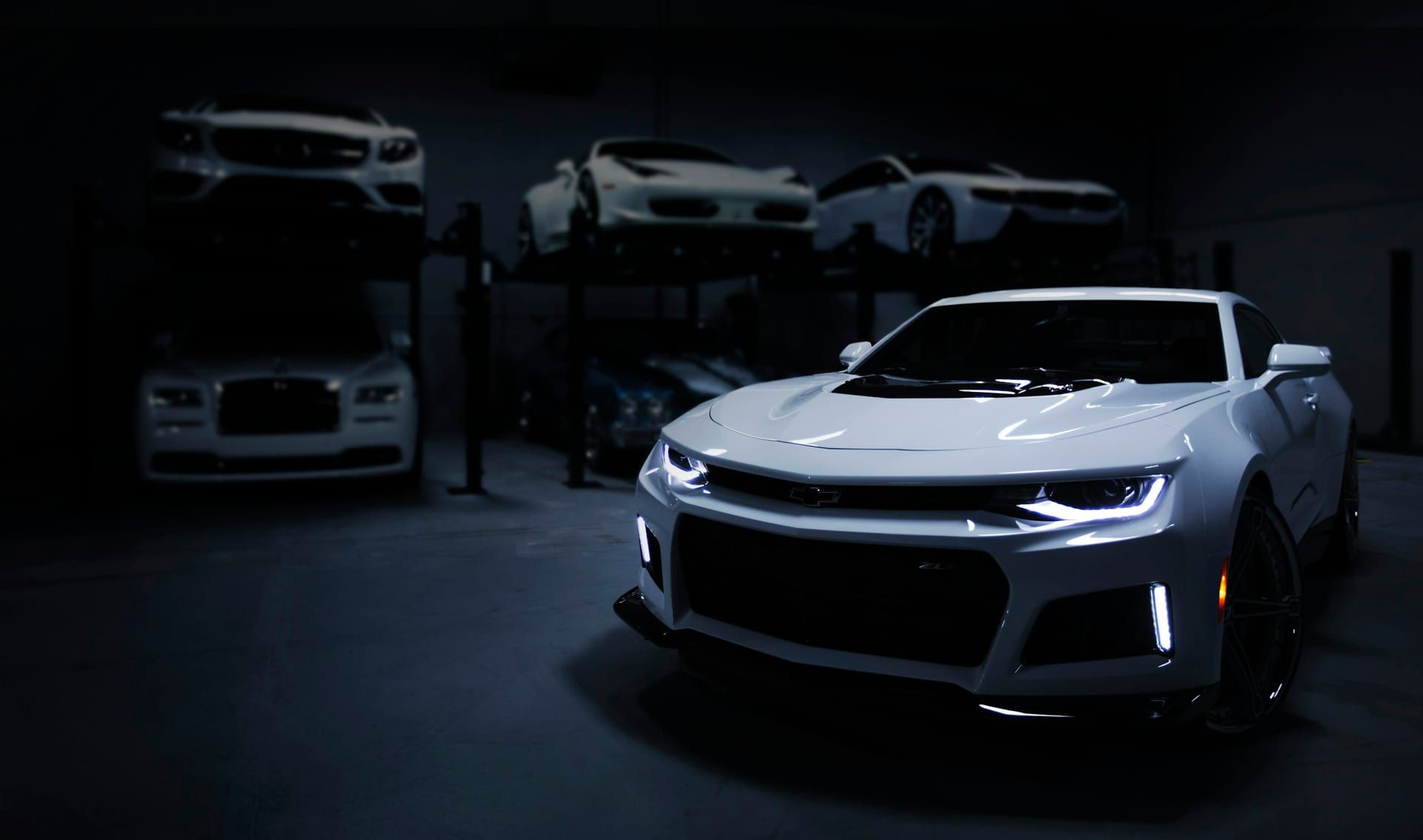 White sports coupe with dark side glass in a dimly lit garage